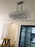 Colorful white glass disc chandelier installed in modern dining room interior