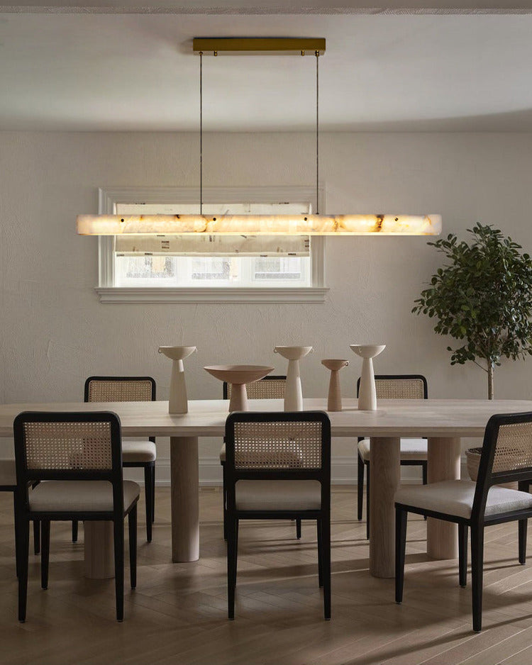 Warm white linear alabaster pendant light over dining room table